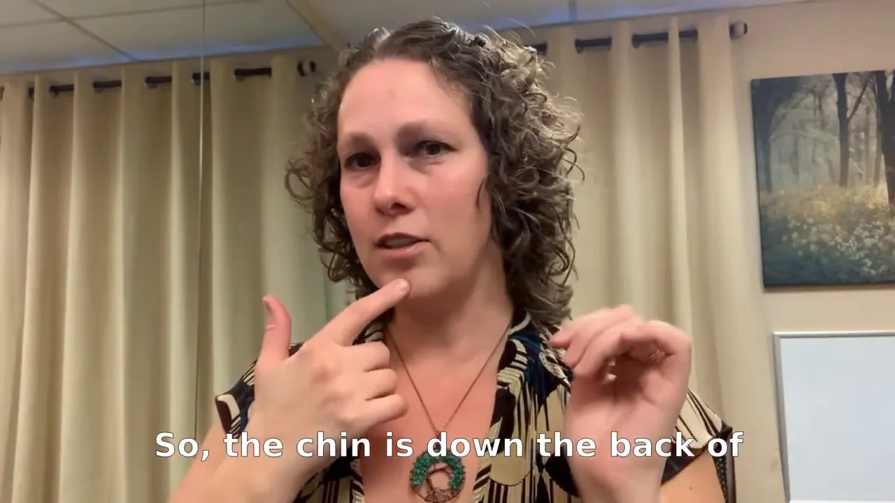 Instructor pointing to chin to demonstrate a gentle chin tuck for neck alignment