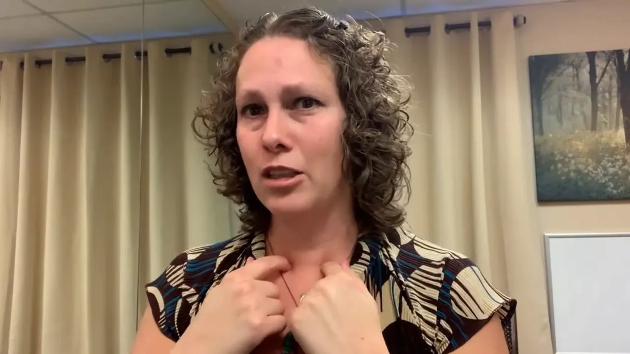 Instructor pointing to the upper chest/neck area to indicate the sternocleidomastoid (SCM) location.