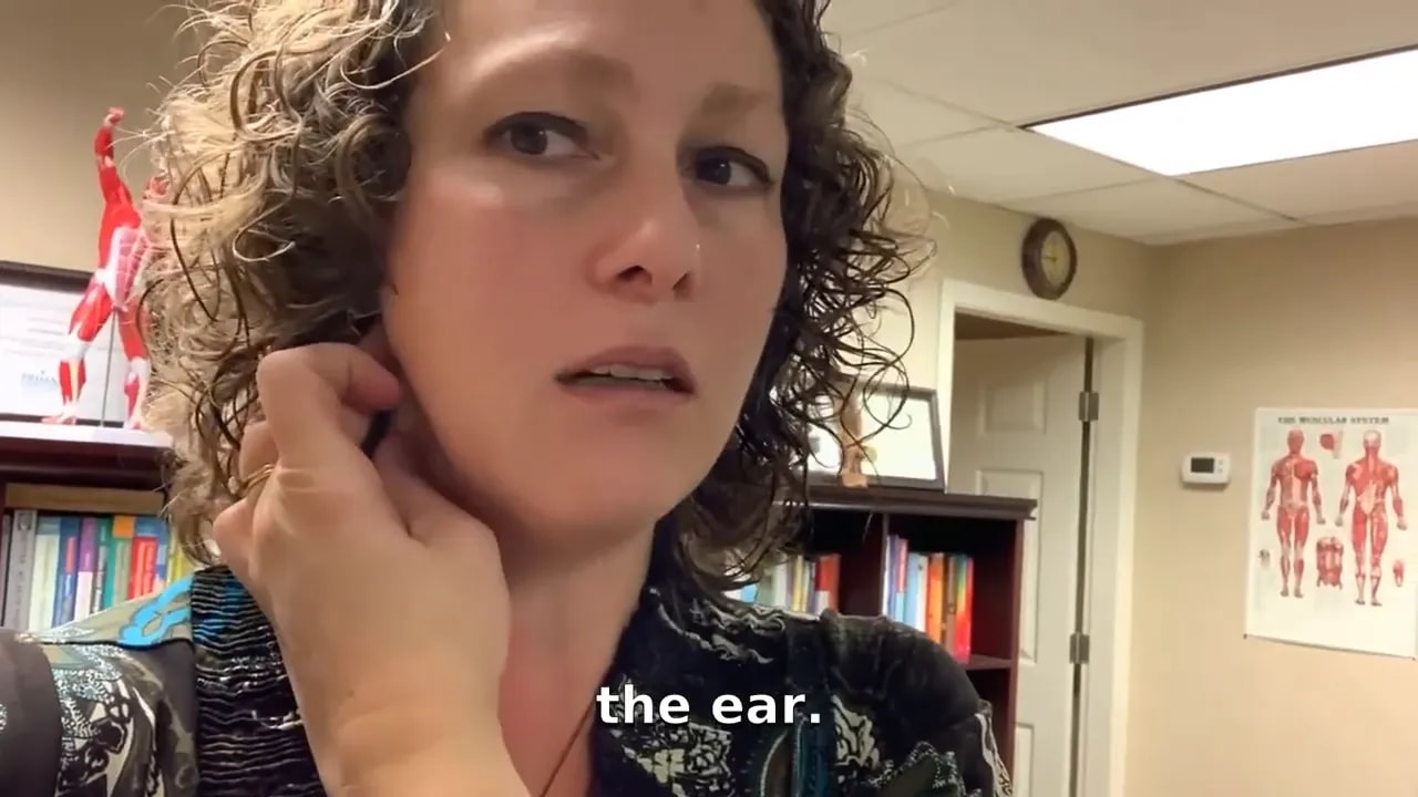 Hand reaching across to palpate the sternocleidomastoid muscle at the side of the neck near the ear.