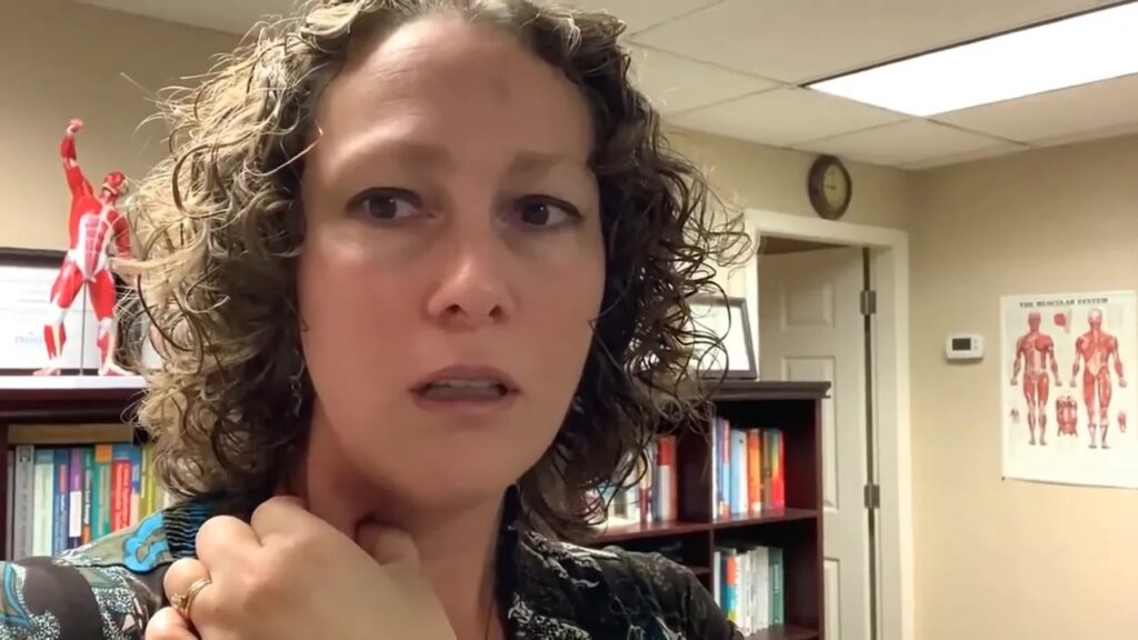 Clear demonstration of a hand grasping the sternocleidomastoid muscle at the side of the neck without subtitle obstruction.